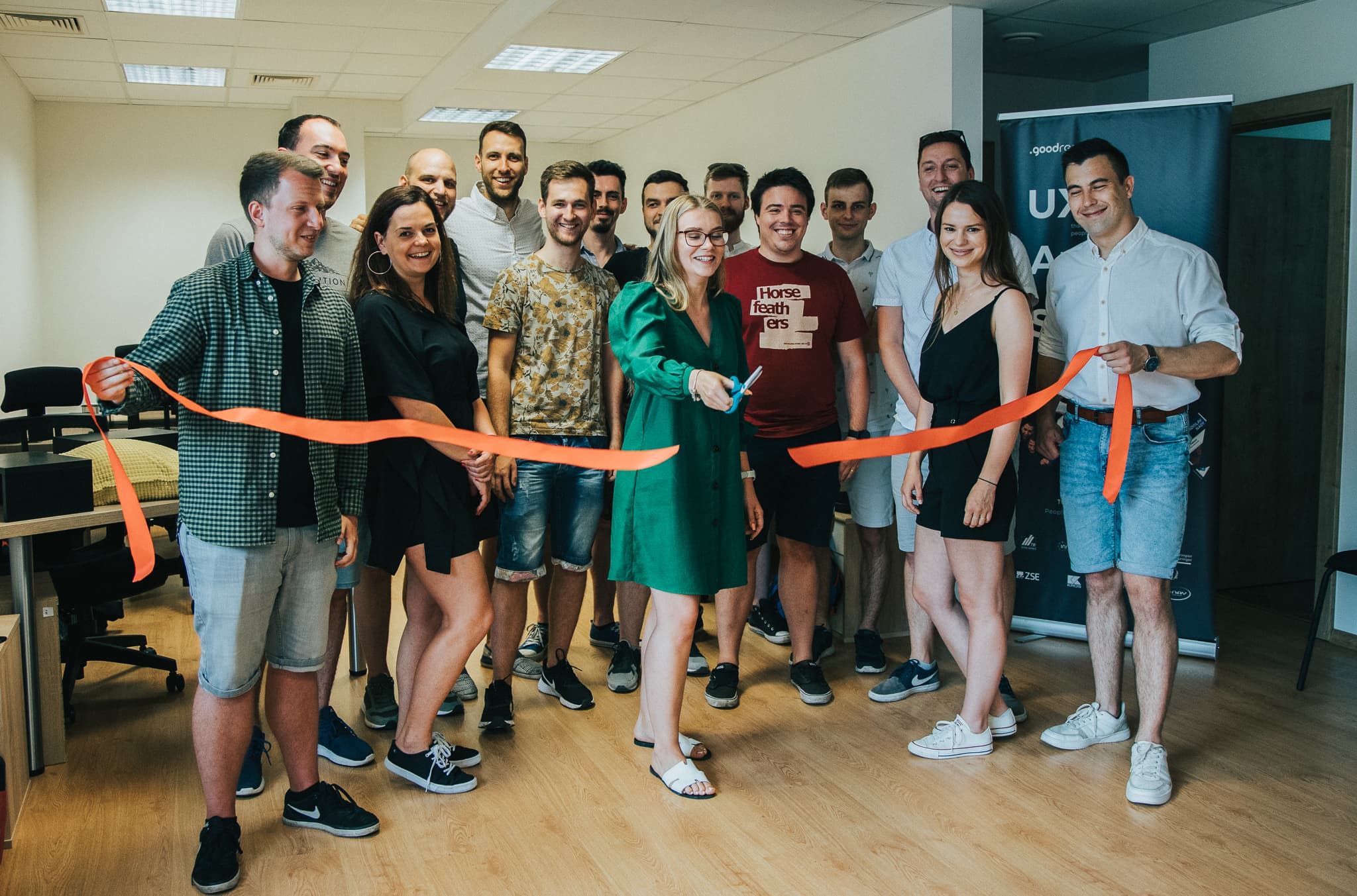 Slávnostné otvorenie novej kancelárie Goodrequest v Košiciach, zachytené momentom prestrihnutia červenej stuhy členmi tímu. V pozadí je pracovný priestor.