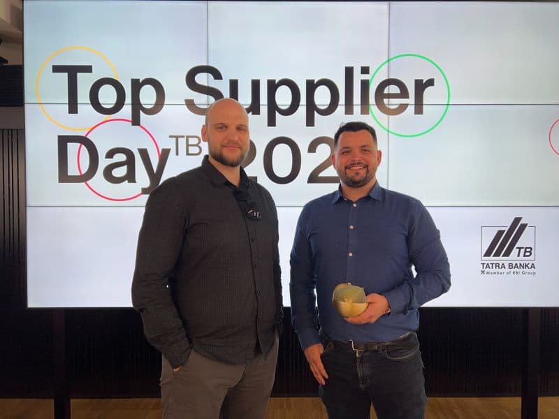 Zástupcovia Goodrequest preberajú ocenenie Top Supplier Day TB 2021 od Tatra Banky počas slávnostného podujatia, pred veľkou obrazovkou s logom banky a nápisom podujatia.