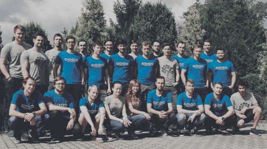 Skupinová fotografia tímu Goodrequest v exteriéri, zachytávajúca členov v modrých a sivých tričkách s logom spoločnosti.