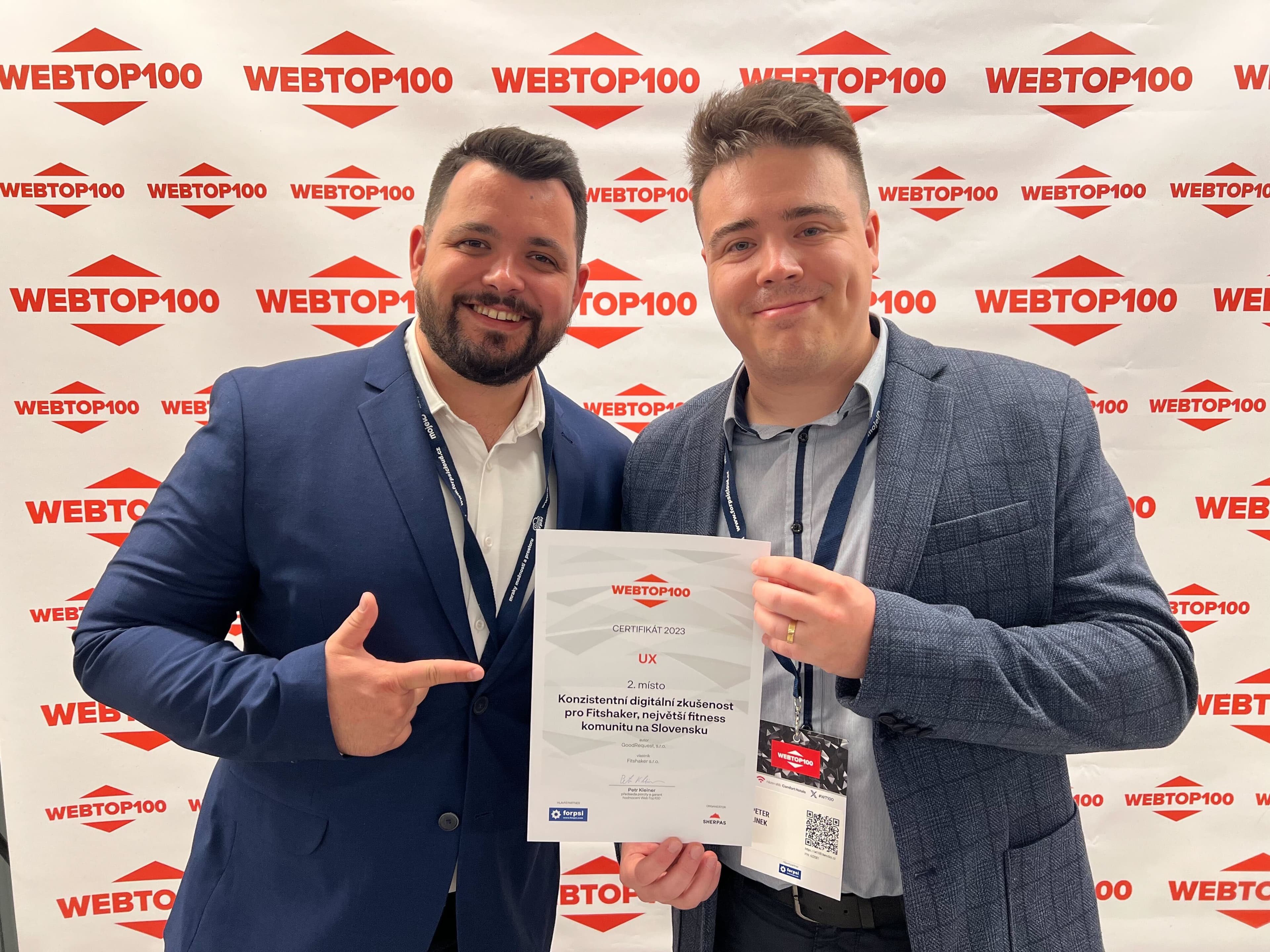 Dvaja muži (Martin Macík a Peter Linek), muž vpravo drží diplom, muž vľavo ukazuje na dilplom, v pozadí stena s viacerými nápismi WEBTOP100.