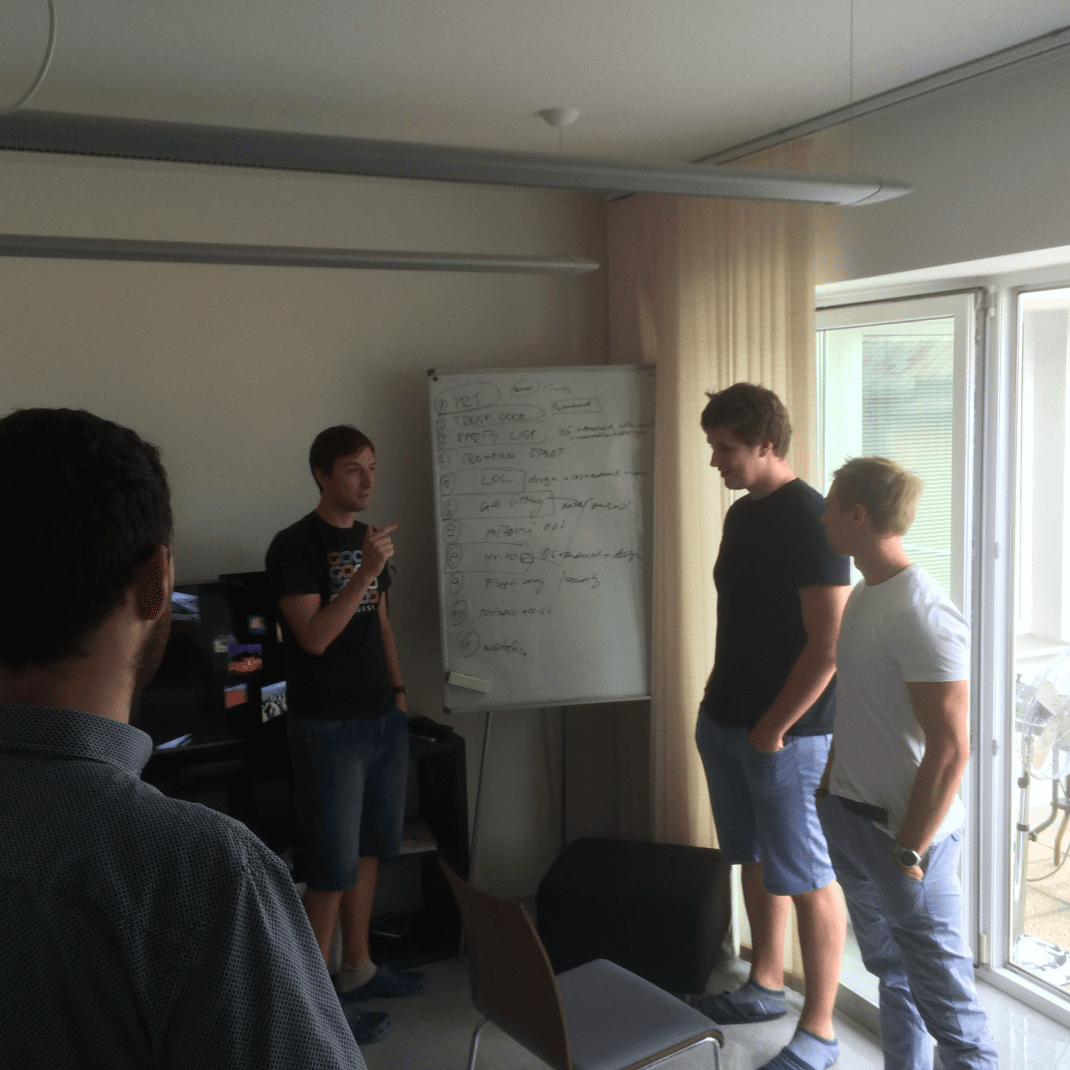 Členovia tímu Goodrequest diskutujú pred whiteboardom počas prvého interného hackathonu, kde sú rozpracované nápady a úlohy ako POC, TRACER, API či webová stránka.