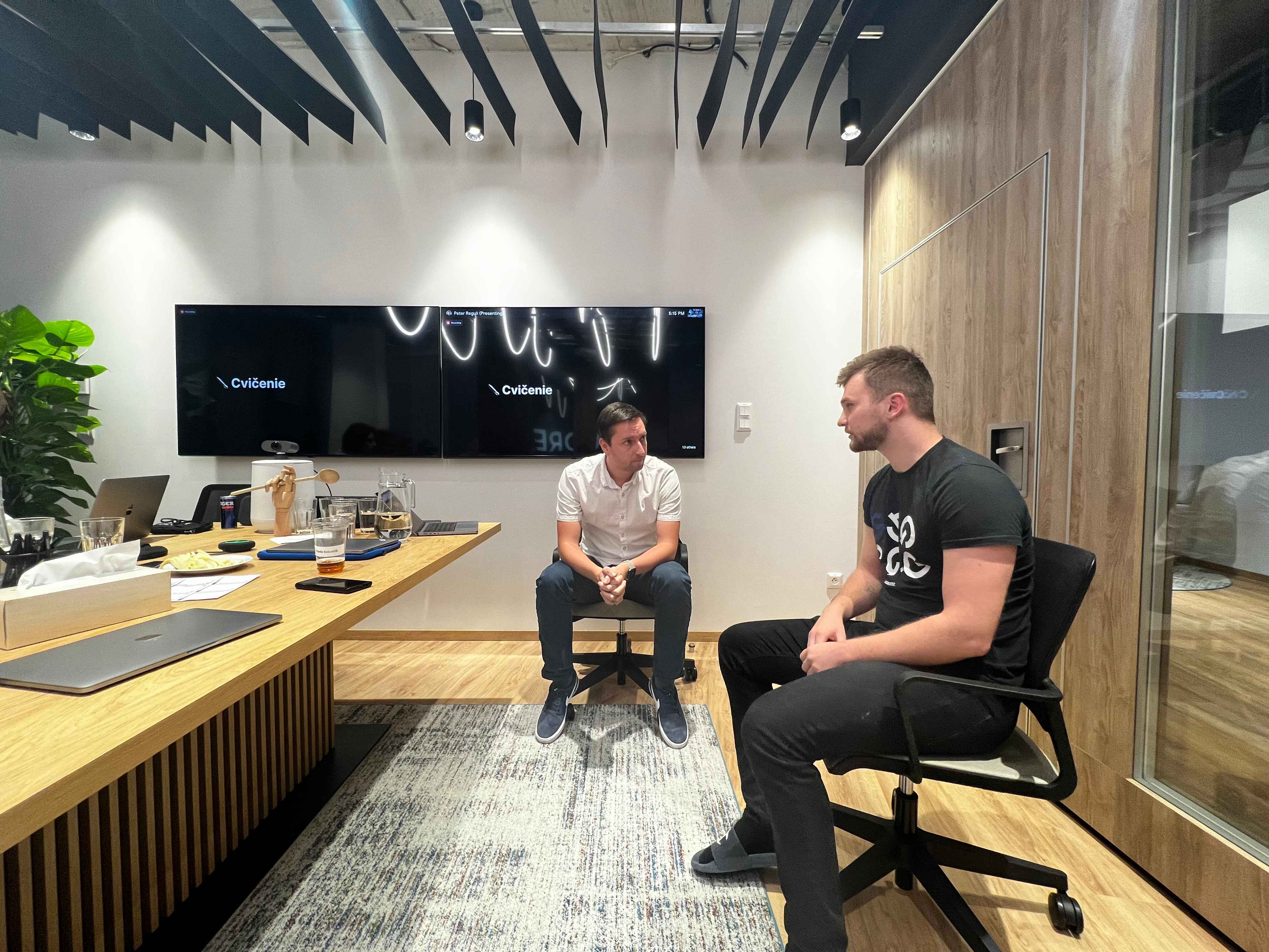 Dve osoby (jednou z nich je CEO spoločnosti) sediace a komunikujúce v zasadacej miestnosti počas Frontend Days, cvičenie - komunikácia.